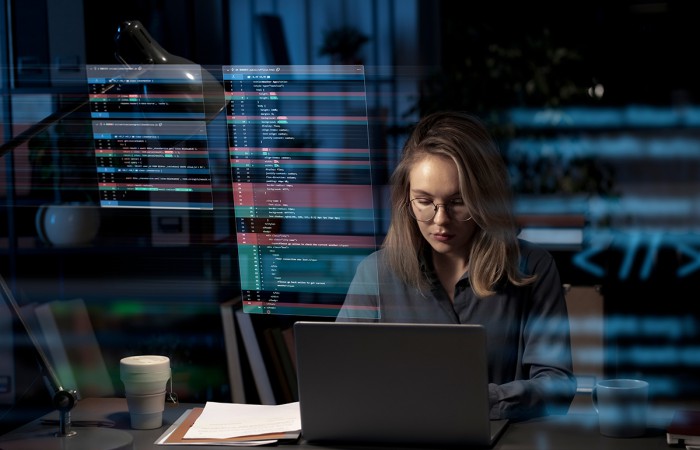 Femme travaillant sur un ordinateur portable avec des interfaces de code en surimpression