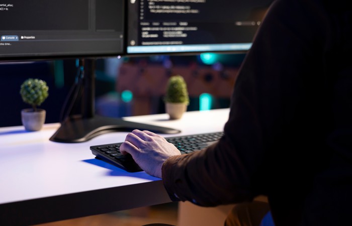 Personne travaillant sur un poste informatique avec plusieurs écrans dans un environnement sécurisé